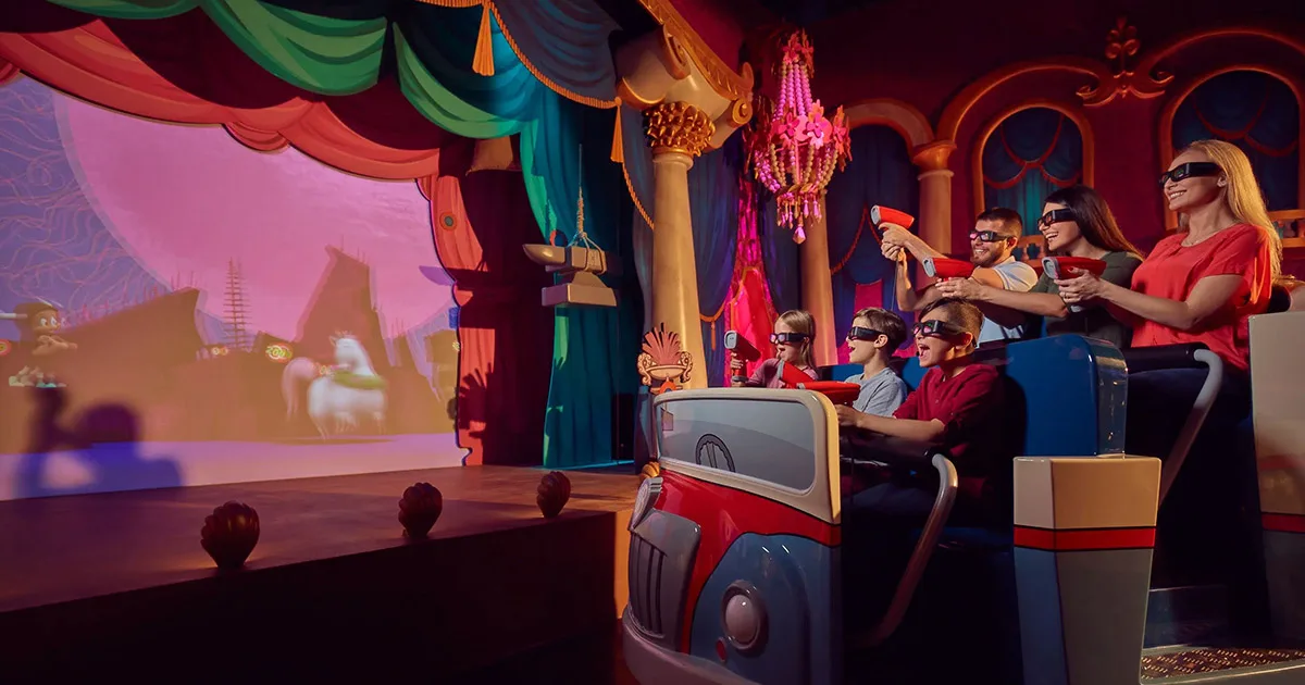 Riders shooting targets on the Ani-Mayhem trackless dark ride