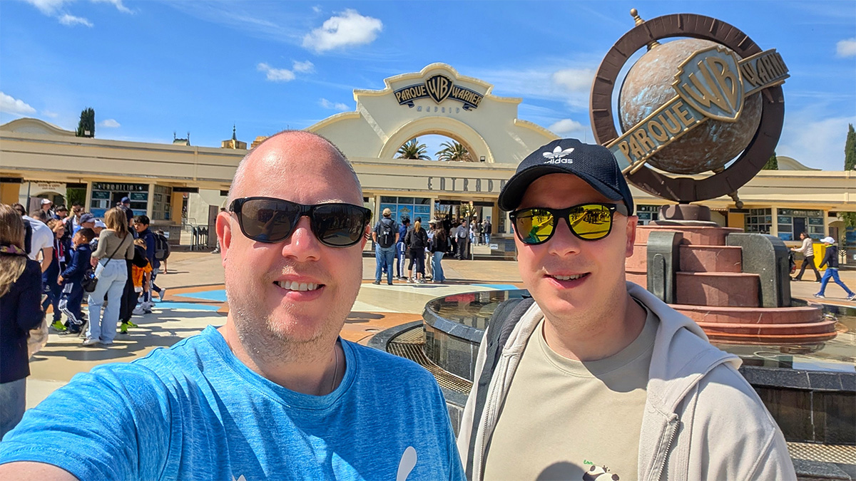 Kolyn and Denis from The Curious Tourists smiling in front of the Hollywood Boulevard entrance arch at Parque Warner Madrid
