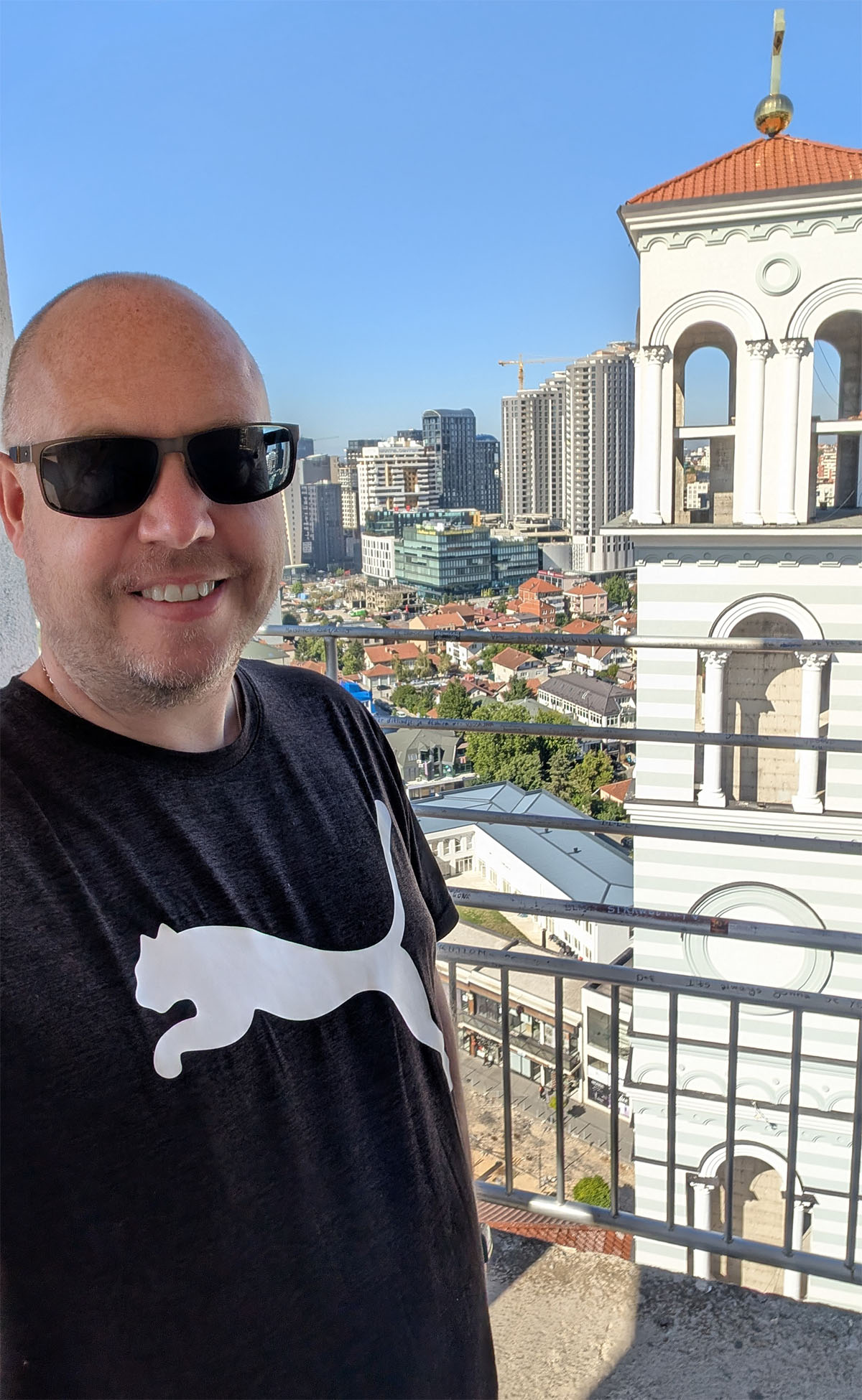 Enjoying the panoramic views over the city from the bell tower on a Pristina day trip