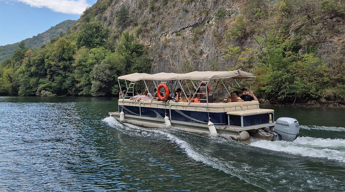 Small tourist boat navigating the gorge towards Vrelo Cave in Matka Canyon