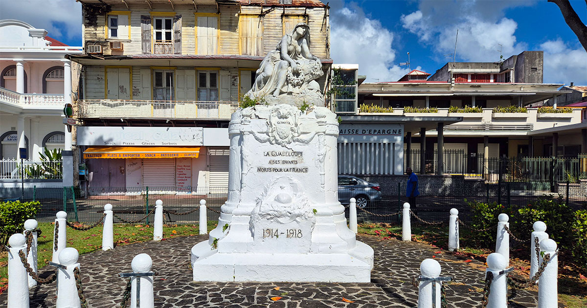 A historic statue surrounded by palm trees in Victory Square, Pointe-à-Pitre